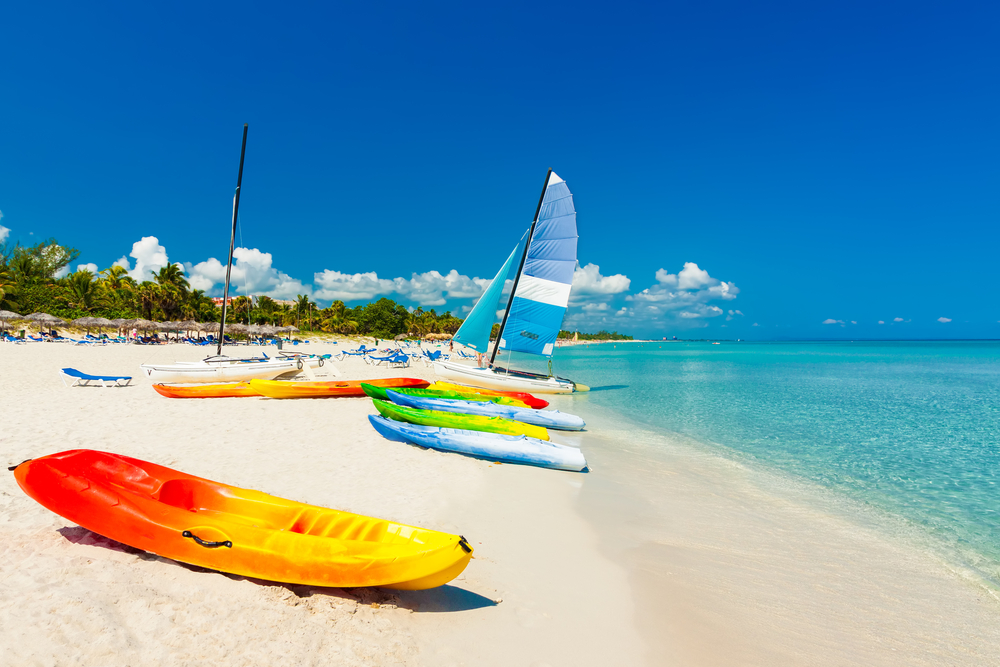 Colorful,Kayaks,And,Sailing,Boats,On,A,Tropical,Beach,In